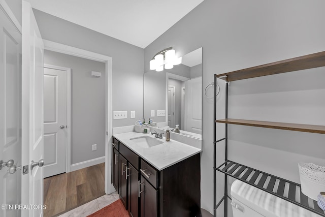 bathroom featuring lofted ceiling, baseboards, wood finished floors, and vanity