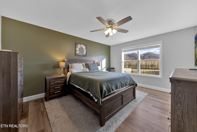 bedroom with wood finished floors, a ceiling fan, and baseboards