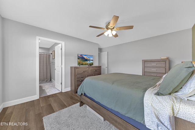 bedroom with ceiling fan, baseboards, wood finished floors, and ensuite bathroom