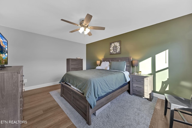 bedroom with a ceiling fan, baseboards, and wood finished floors