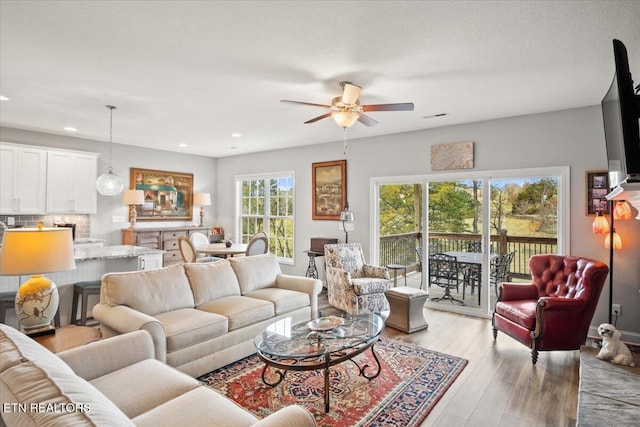 living room featuring ceiling fan, visible vents, light wood-style flooring, and recessed lighting