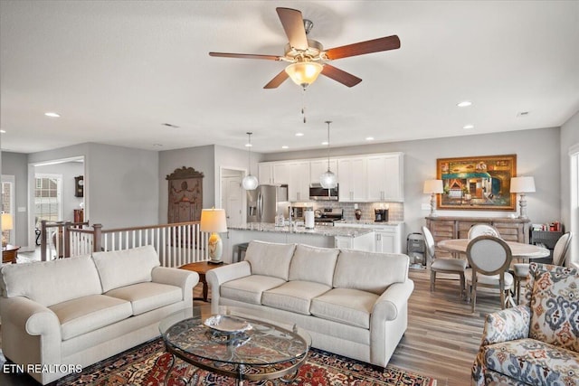 living room featuring light wood finished floors, ceiling fan, and recessed lighting