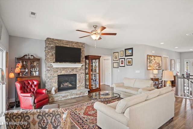 living area with a stone fireplace, recessed lighting, wood finished floors, visible vents, and a ceiling fan