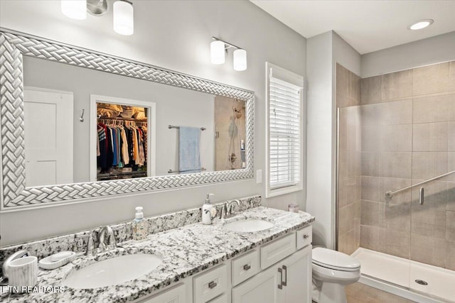 full bathroom featuring double vanity, a sink, toilet, and a shower stall