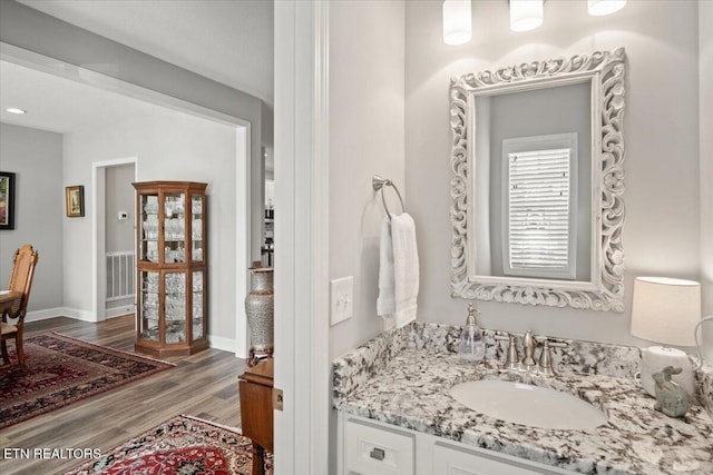 bathroom featuring baseboards, wood finished floors, and vanity