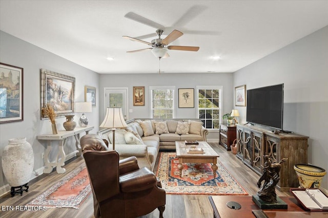 living area with baseboards, a ceiling fan, and wood finished floors