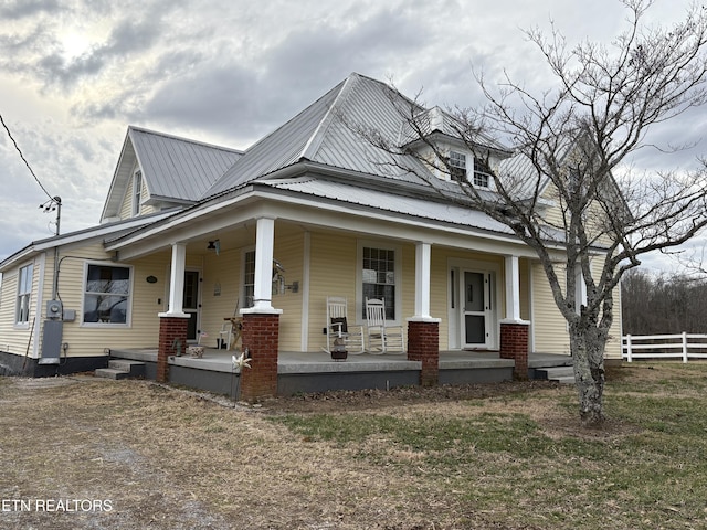 view of front of home featuring metal roof, fence, and a porch