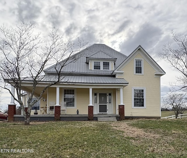 view of front of property with covered porch, metal roof, and a front lawn