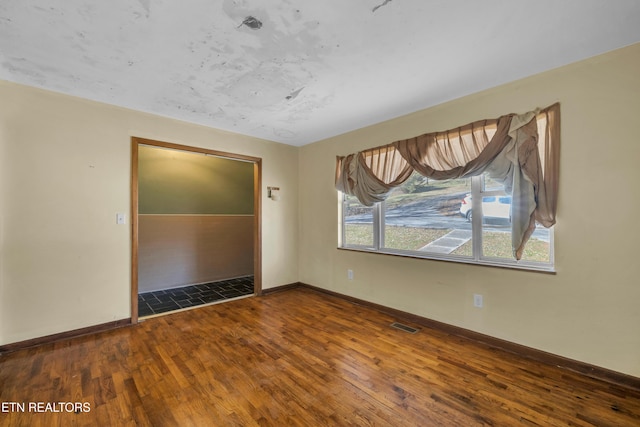 spare room featuring hardwood / wood-style flooring and baseboards