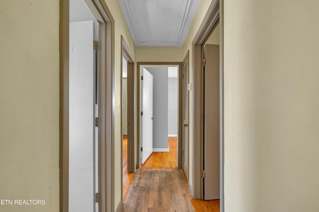 corridor featuring attic access and wood finished floors