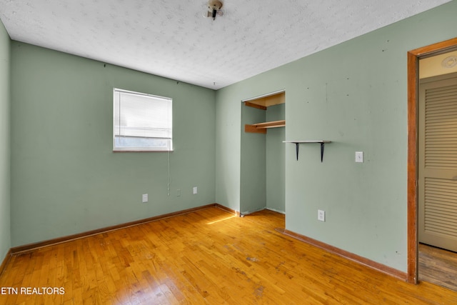 unfurnished bedroom with a textured ceiling, baseboards, and hardwood / wood-style flooring