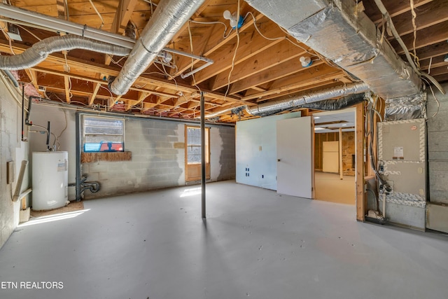 basement featuring water heater and freestanding refrigerator