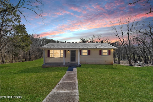 view of front of property featuring metal roof and a lawn