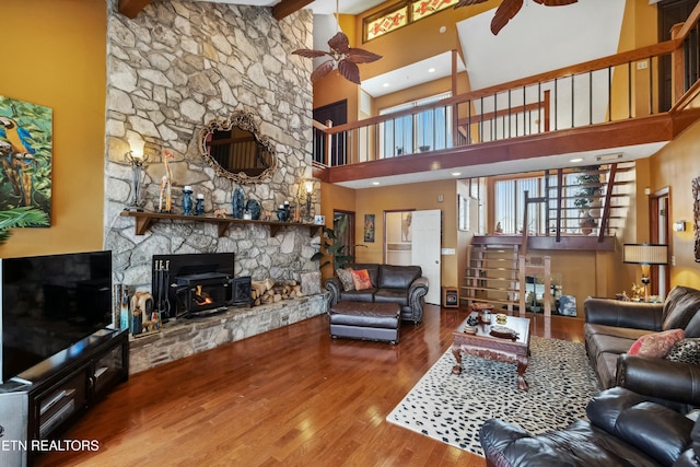 living area with a ceiling fan, wood finished floors, and beamed ceiling