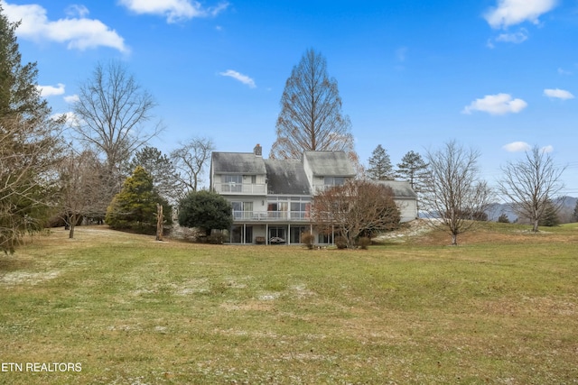 back of property with a lawn and a chimney