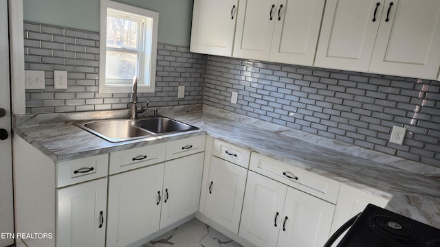 kitchen with marble finish floor, white cabinetry, decorative backsplash, and a sink