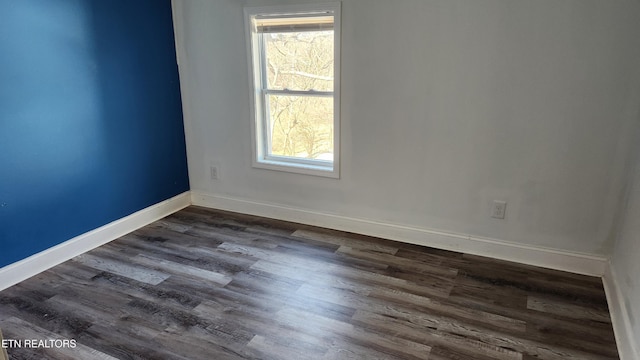empty room featuring dark wood-style flooring, a wealth of natural light, and baseboards