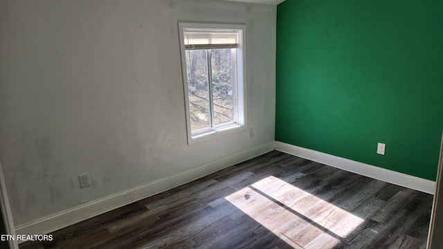 empty room featuring dark wood-style floors and baseboards