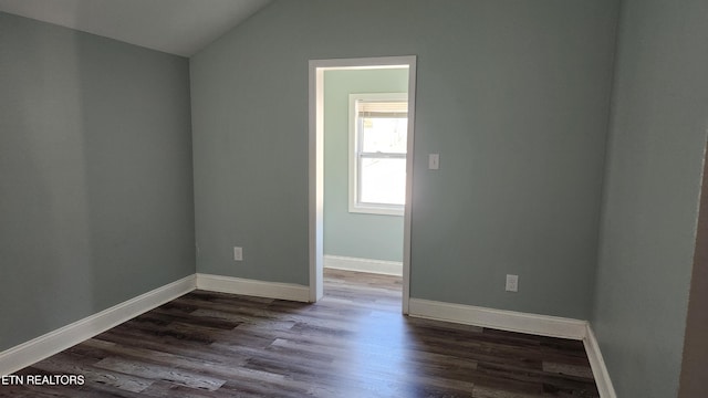 spare room with lofted ceiling, dark wood-type flooring, and baseboards