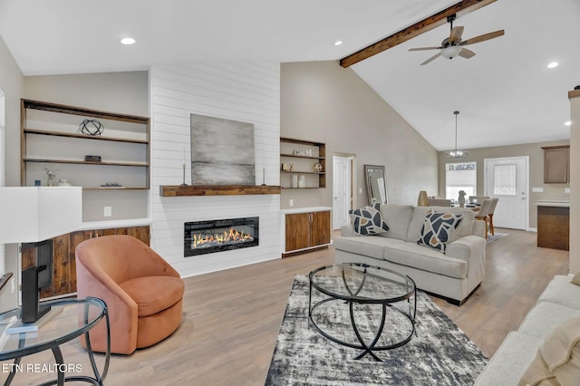 living room with a fireplace, light wood finished floors, ceiling fan, high vaulted ceiling, and beamed ceiling