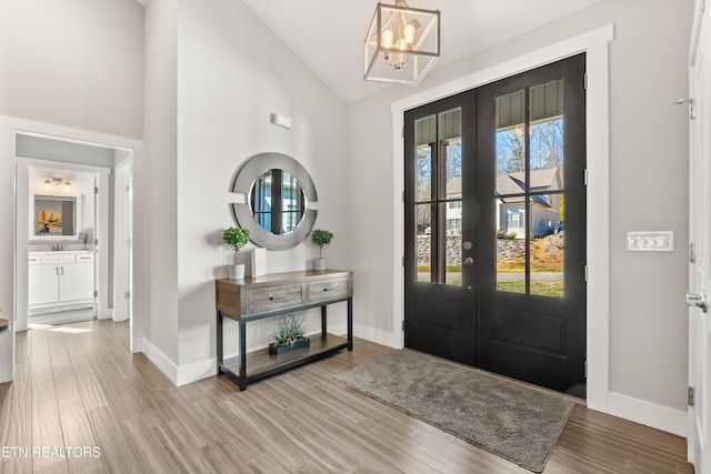 foyer with lofted ceiling, french doors, baseboards, and wood finished floors