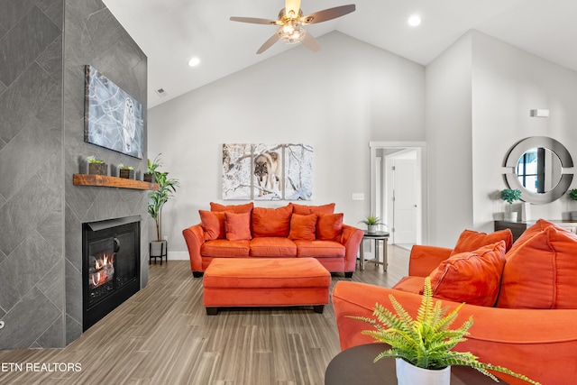 living room with high vaulted ceiling, a fireplace, ceiling fan, and wood finished floors