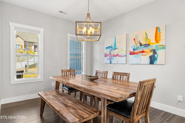 dining area with dark wood-style floors, baseboards, and an inviting chandelier