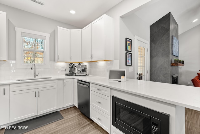 kitchen with built in microwave, light countertops, a sink, and backsplash