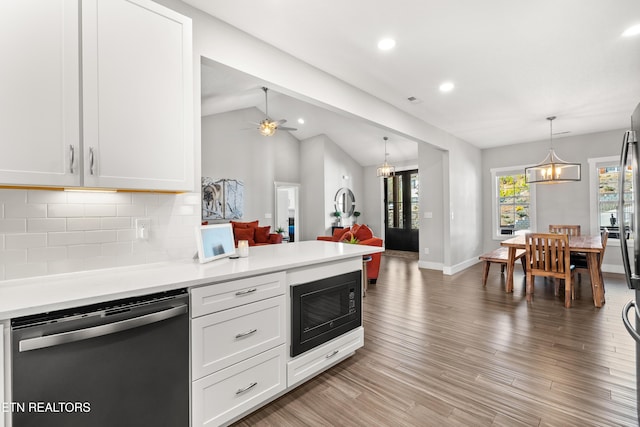 kitchen with black microwave, light wood-style flooring, light countertops, backsplash, and dishwasher