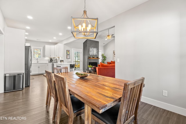 dining space with lofted ceiling, a fireplace, baseboards, and wood finished floors