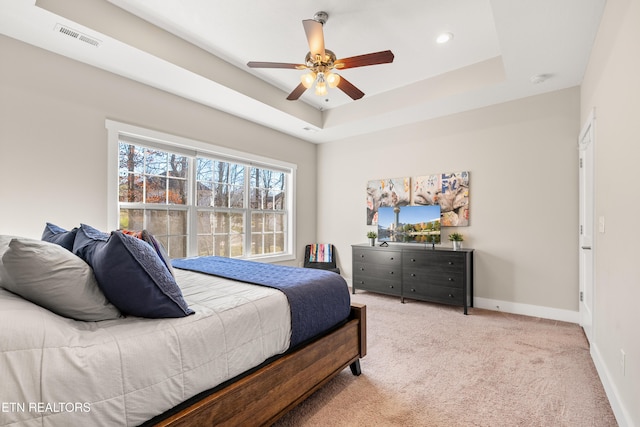 bedroom featuring baseboards, visible vents, a raised ceiling, a ceiling fan, and light colored carpet