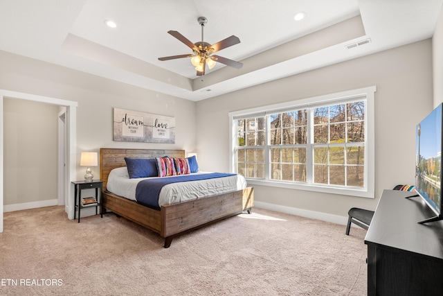 bedroom with a raised ceiling, visible vents, light carpet, and baseboards