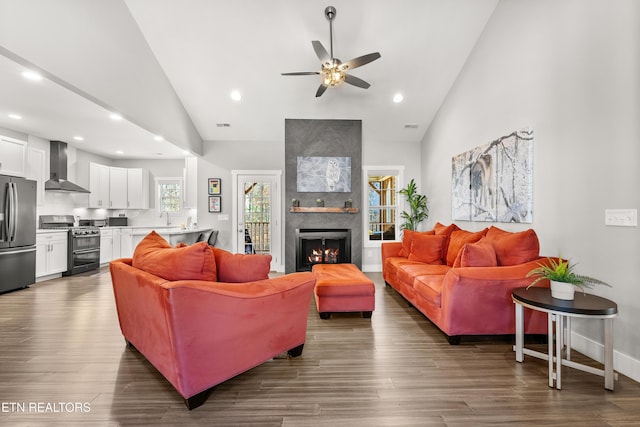 living room featuring dark wood-type flooring, high vaulted ceiling, and a tiled fireplace