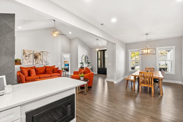 interior space featuring dark wood-type flooring, visible vents, vaulted ceiling, and baseboards