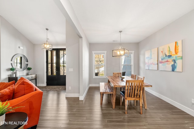 dining space featuring a chandelier, dark wood-type flooring, and baseboards