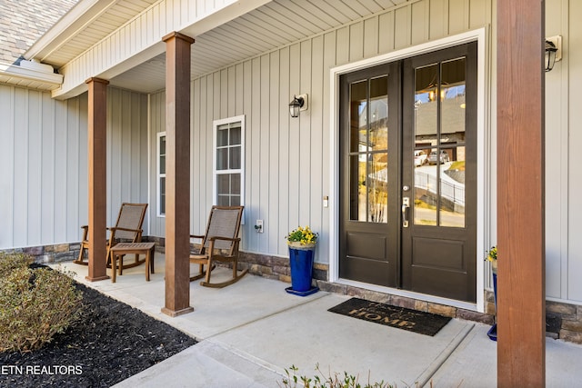 entrance to property featuring a shingled roof and covered porch