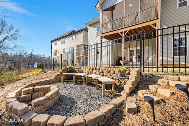 back of property with a sunroom, a patio area, fence, a residential view, and a fire pit