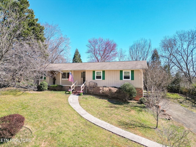 ranch-style home featuring aphalt driveway, fence, and a front lawn