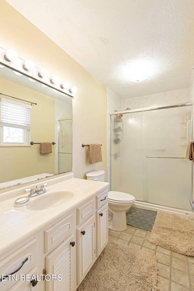 bathroom with toilet, a stall shower, a textured ceiling, and vanity