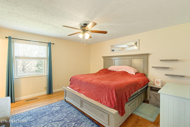 bedroom with baseboards, visible vents, a ceiling fan, light wood-style flooring, and a textured ceiling