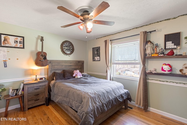 bedroom with ceiling fan, a textured ceiling, baseboards, and wood finished floors