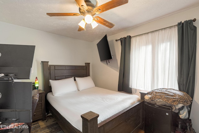 bedroom with multiple windows, ceiling fan, and a textured ceiling