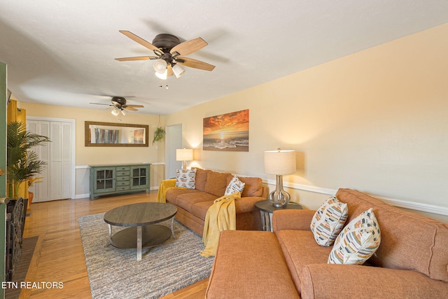 living area with a ceiling fan, light wood-style flooring, and baseboards