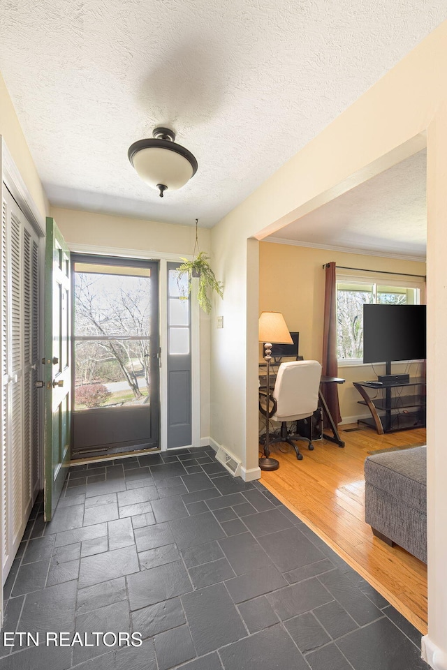 foyer entrance with dark wood-style flooring, a textured ceiling, and baseboards