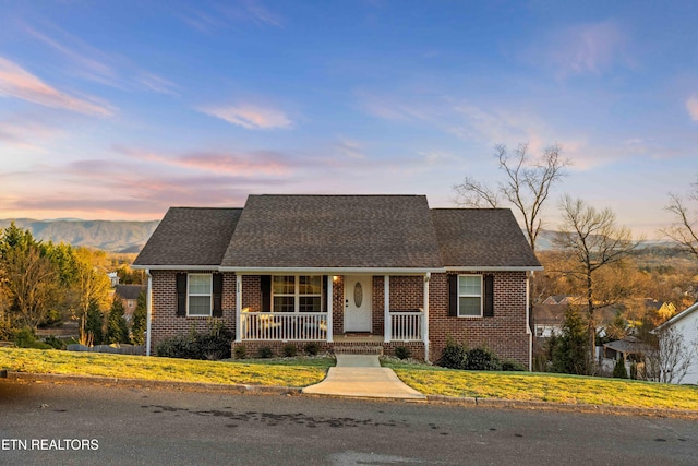 view of front of property featuring a shingled roof, a porch, and brick siding