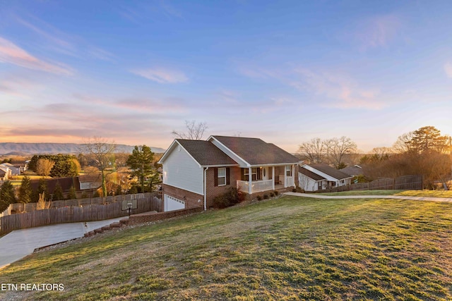 view of front of property with a garage, covered porch, fence, a front lawn, and brick siding