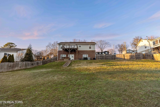 rear view of property with brick siding, a lawn, and a fenced backyard