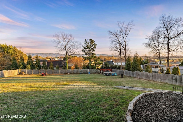 yard at dusk featuring a fenced backyard