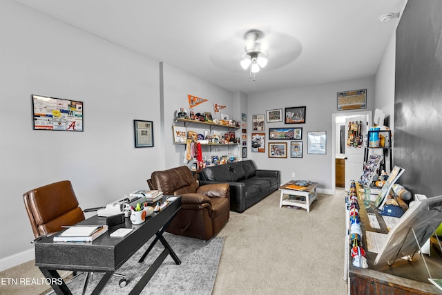 carpeted living area with ceiling fan and baseboards