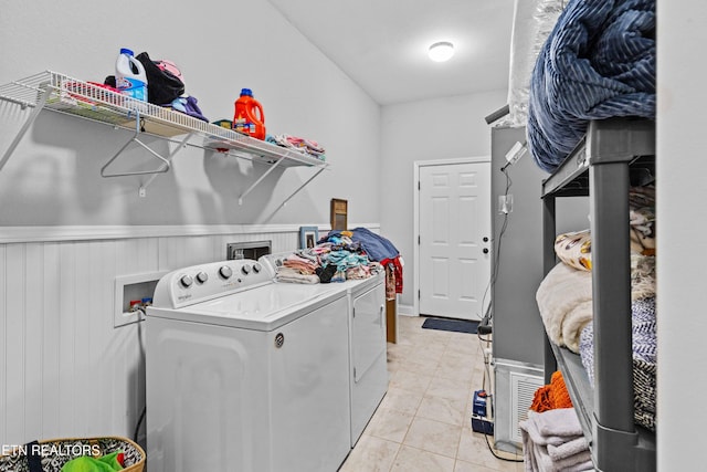 clothes washing area featuring laundry area, wainscoting, light tile patterned floors, and washing machine and clothes dryer